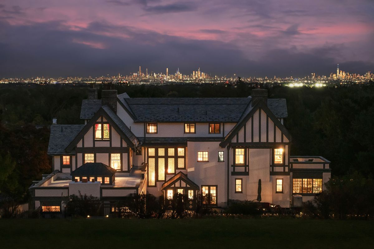 The rear of 184 Upper Mountain Avenue lit at dusk with the New York City skyline glowing on the horizon